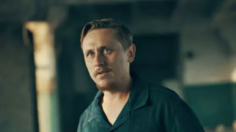 Ben Steele/BBC Dima, wearing a blue collared t-shirt, speaks to the BBC in an undisclosed warehouse.