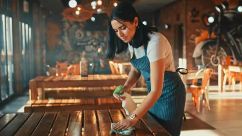 Woman working in a restaurant cleaning tables