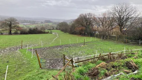 Green fields with a section cordoned off using white plastic posts and wire