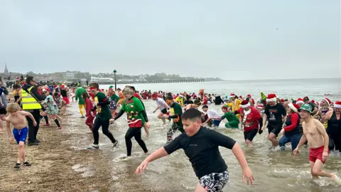 St Elizabeth Hospice Christmas Day dippers walking out of the sea in Felixstowe