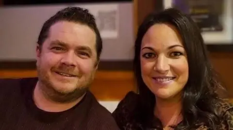 Mark and Ellen sit side  by side, smiling. Ellen has hair much darker than Mark;s and show her teeth when she smiles. She wears an animal print top. 