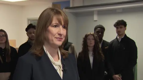 Rachel Reeves addresses the media wearing a blue suit jacket and white blouse