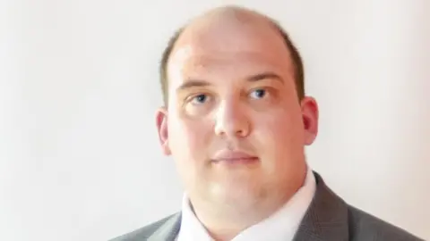 North Northamptonshire Council Matt Keane with very short brown hair wearing a grey jacket