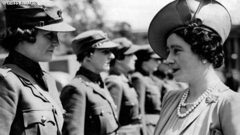 Queen Elizabeth, The Queen Mother, inspects a line of women working for the war effort