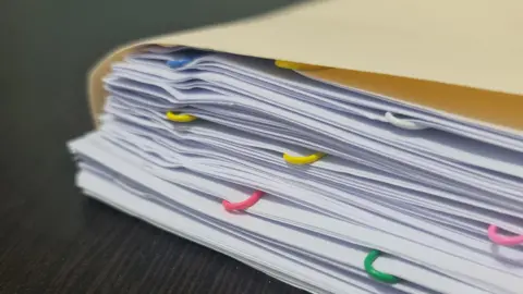 Getty Images Stacks of white paper with different coloured paper clips 