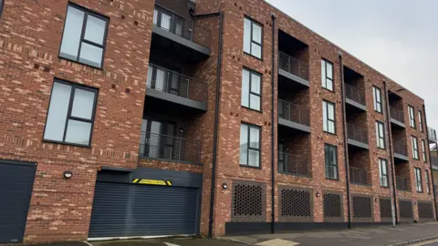 Danny Fullbrook/BBC Several windows and balconies are visible at Birch Court across four floors.