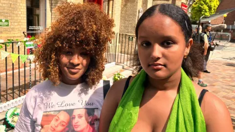 Hemen, who is wearing a green scarf, is pictured with another aunt looking at the camera.
