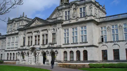 The outside of the main Cardiff University building with a pathway leading up to the entrance seen at the bottom.