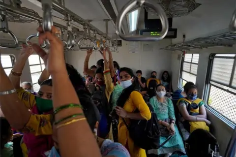 Reuters Women covering their faces with protective masks commute in a suburban train after authorities resumed the train services for all commuters after it was shut down to prevent the spread of the coronavirus disease (COVID-19) in Mumbai, India, February 1, 2021