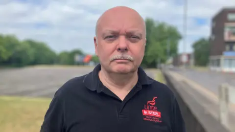 BBC Mr Foster wears a black top with "Unite in Steel" red logo on it.