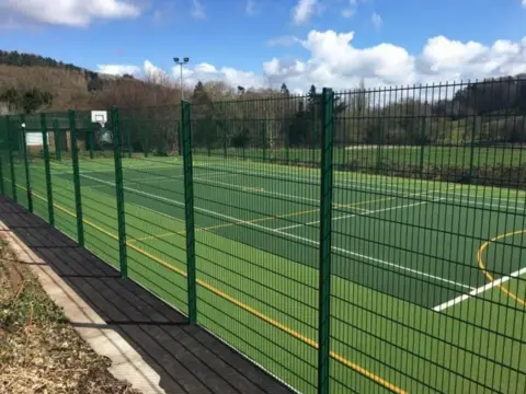 Cestari Architects Ltd An image of the proposed new floodlit sports pitch at Worplesdon Primary School. Green fencing can be seen around the perimeter of the pitch. 