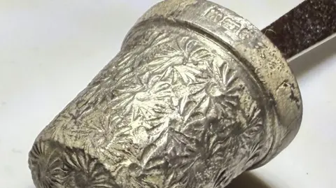 Tommy Coleman A silver thimble is displayed on the end of a pen.