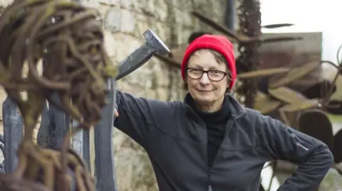 Supplied Hilary Cartmel posing with some of her work in a yard.