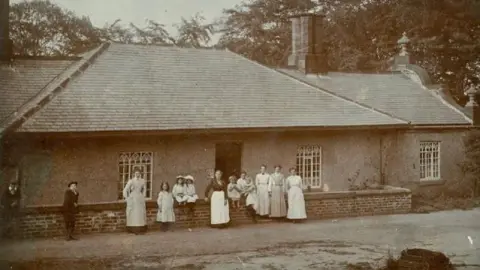 BIRLEY SPA PRESERVATION TRUST A historic photo of the spa, with its staff and their children stood in front of it.