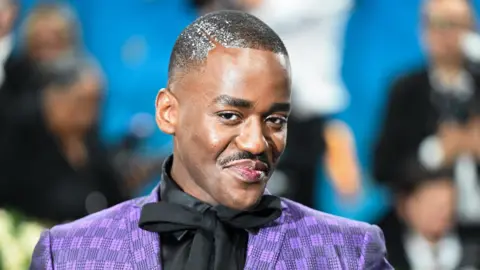 Ncuti Gatwa in a purple suit and black shirt
