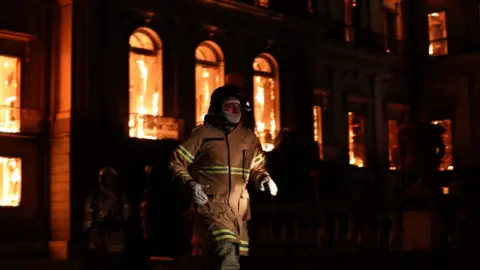 EPA A firefighter walks in front of the National Museum of Rio de Janeiro, one of the oldest in Brazil, as it is consumed by flames due to a major fire, in Rio de Janeiro, Brazil, 2 September 2018.