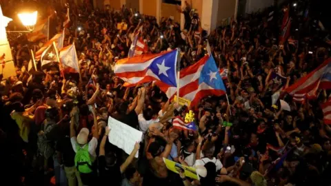 Reuters People celebrate in San Juan after the news that Governor Ricardo Rosselló is to resign. Photo: 24 July 2019