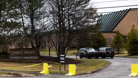 Law enforcement officers monitor near the front entrance of Temple Israel