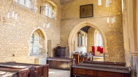Bidwells The inside of a 12 century church with wooden pews, large arches and old bay windows.