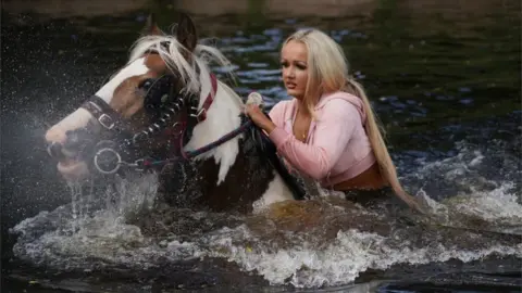 PA Media Girl on horse in river