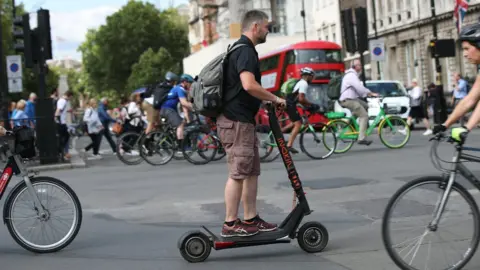 PA Media Man on an e-scooter in London