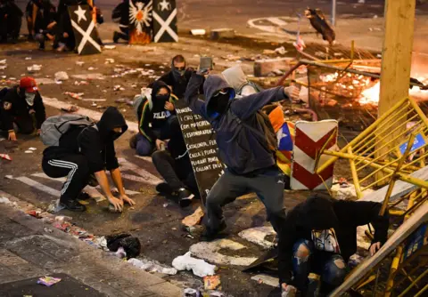 Getty Images Protesters throw rocks at riot police in Barcelona