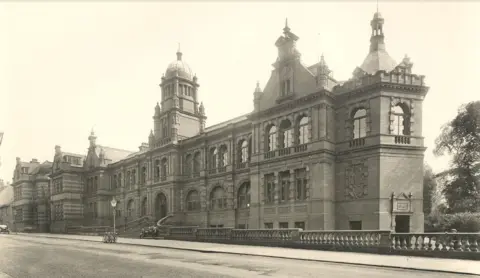 The Story/Durham County Council An sepia picture of a large Victorian-style hall, with arched windows, a gothic roofline and a domed tower in the middle.