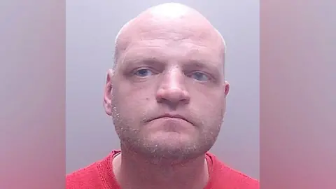 Cambridgeshire Constabulary Picture of Aigars Balsevics, he is bald and wearing a red t-shirt