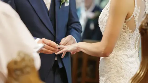 Getty A groom is putting a wedding ring on a bride's finger