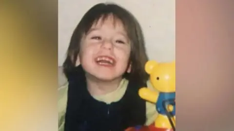 supplied Little girl smiling at the camera with toy on one side