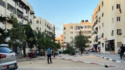 Qutaiba Kolthoum  A daytime shot of Al-Zahra before the bombing, with a large square surrounded by blocks of apartments