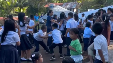 Children at a school in the Philippines react after an earthquake strikes, causing an outdoor structure to collapse