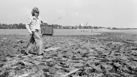 Birmingham Post & Mail Archive/Mirrorpix via Getty Images A black and white photo of a young boy going fishing at a dried out reservoir in the summer of 1976.