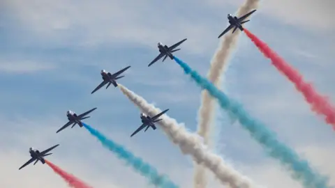 The RAF Red Arrows flying in formation, with red, white and blue vapour trails behind them