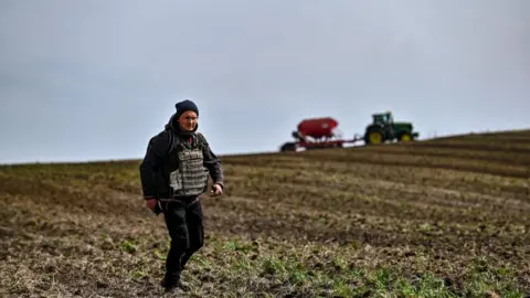 Getty Images A farmer wears a flak jacket during the spring sowing in Zaporizhzhia region, south-eastern Ukraine