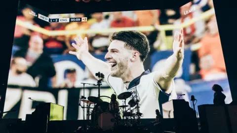 Chris Phelps Tela grande mostrando Declan Rice da Inglaterra comemorando, com bateria em primeiro plano