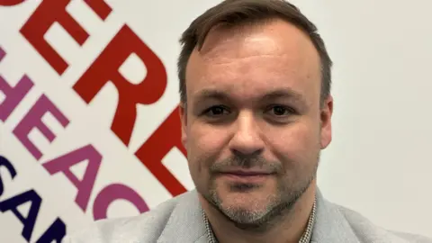 Andrew Sinclair/BBC Terry Jermy looks at camera. He has a moustache and thin beard and is wearing a grey jacket.