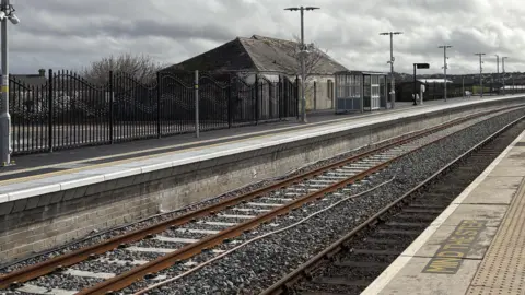 Newquay railway station's new track and platform heading off into the distance with a bus shelter and lighting on the platform 