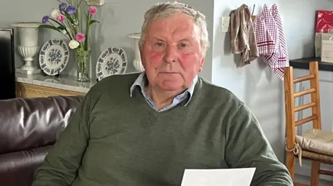 Tom Wall in his home with documents from his time at Christian Brothers