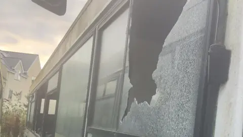 Sean Harvey A smashed window of a coach 