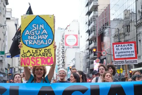 Getty Images A woman holds a sign at a protest which says in Spanish 'without water there are no jobs, hands off the glacier law'