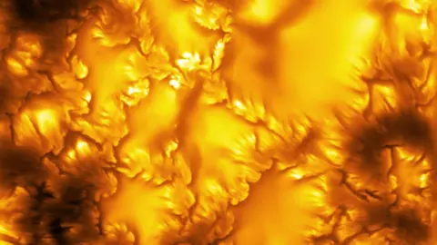 The image shows an extreme close-up of the surface of the Sun, captured by the world's most powerful solar telescope. It shows a fiery orange glow with patterns that look almost like etchings of leaves across the surface. These patterns are evidence of "swirls of instability" on the Sun's surface.