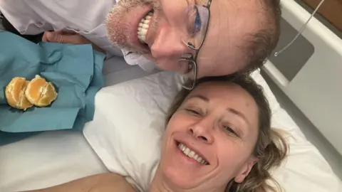 Family photo Dr Hard lying in a hospital in Malta with husband Jake by her side 