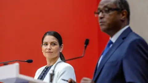 Reuters Priti Patel looks on as Foreign Minister Vincent Biruta addresses a news conference