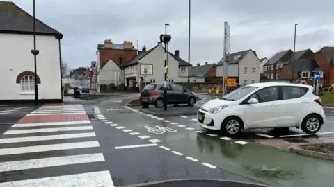 Cars on a roundabout with dedicated cycle lane and pedestrian crossing
