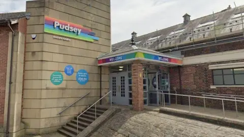 Google The outside of Pudsey Leisure Centre, as denoted by signage over the entrance. The front door is at the top of a set of steps.