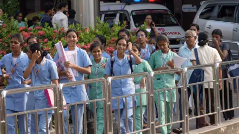 Wisnu Vardhan gambar menunjukkan bahwa mahasiswa keperawatan tertawa dan mengobrol di luar kampus perguruan tinggi kedokteran di Kerala, India. 