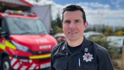 Michael Humphreys from Scottish Fire and Rescue Service stands in front of a small fire appliance in the Highlands