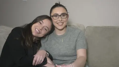 Cara and Elena Lang hug each other and smile as they remember their dad, Mark