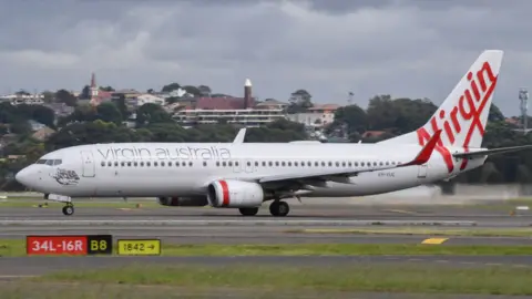 Getty Images A Virgin Australia Boeing 737-800 series aircraft on the runway at Sydney's main international airport.